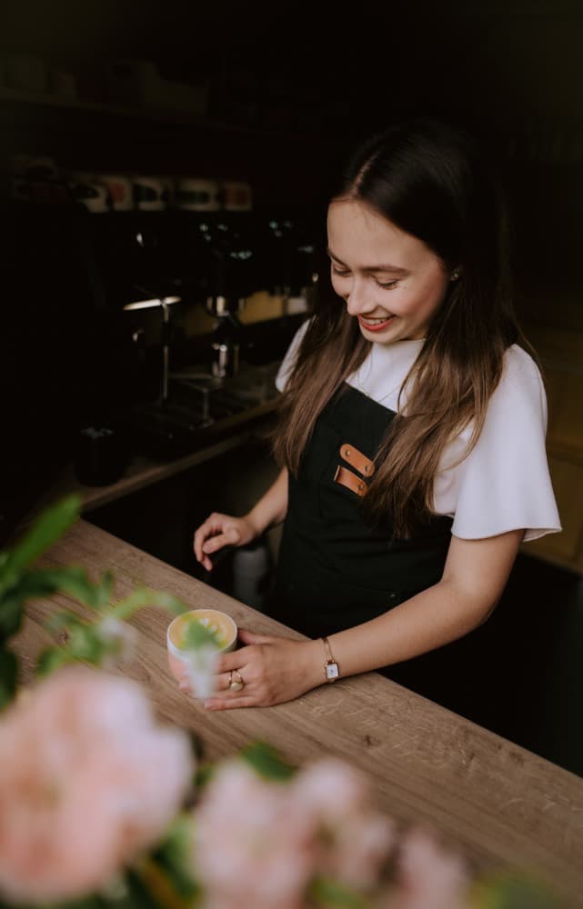Eliška připravuje latte za barem